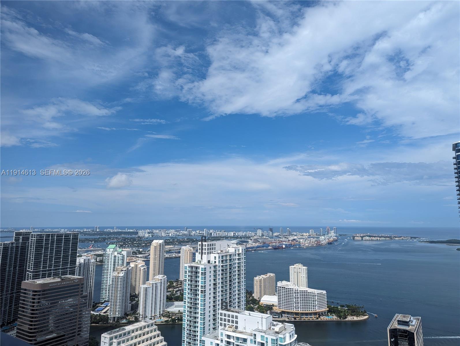 A high-angle view shows a coastal city skyline with numerous skyscrapers overlooking a large bay — 1000 Brickell Plz # 2101, Miami FL 33131, MIAMI, FL