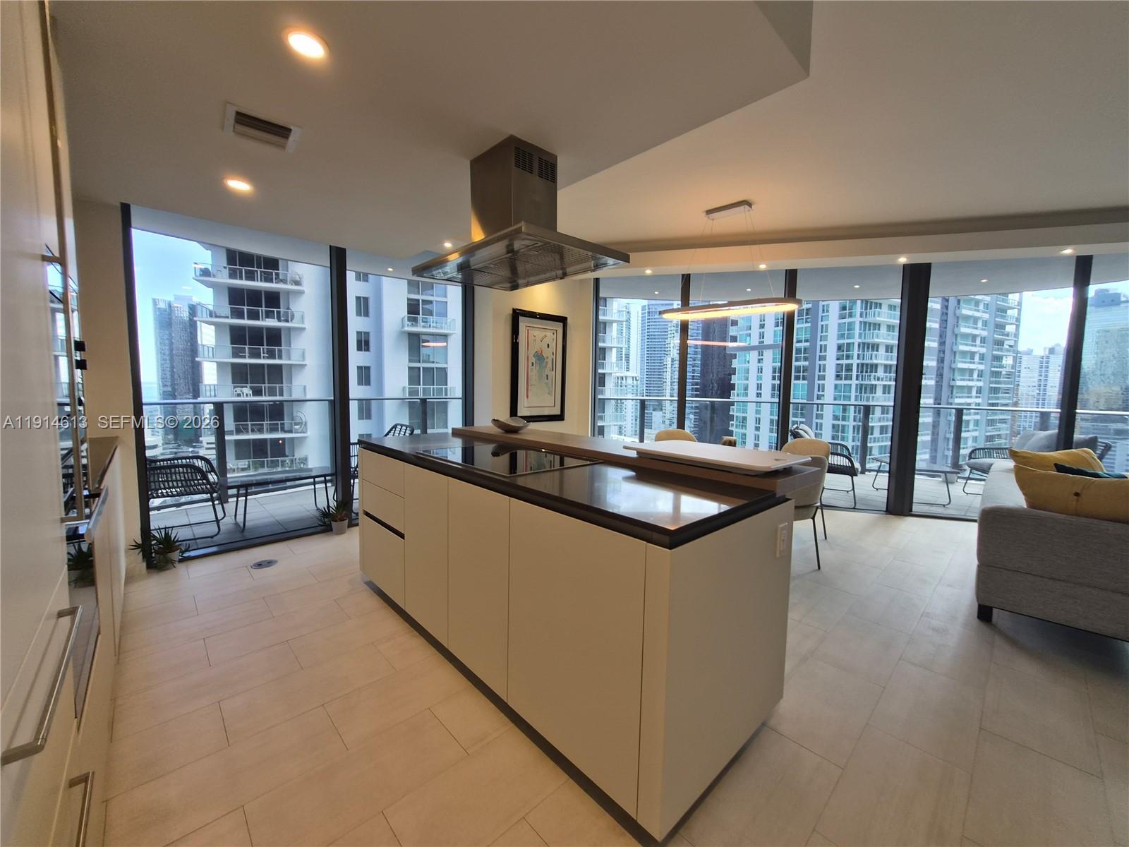 A modern kitchen island with a cooktop sits in an apartment with floor-to-ceiling windows — 1000 Brickell Plz # 2101, Miami FL 33131, MIAMI, FL