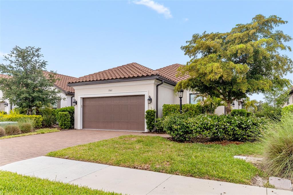A single-story house with a brown garage door, tiled roof, and landscaped front yard — 5362 CICERONE STREET, SARASOTA, FL