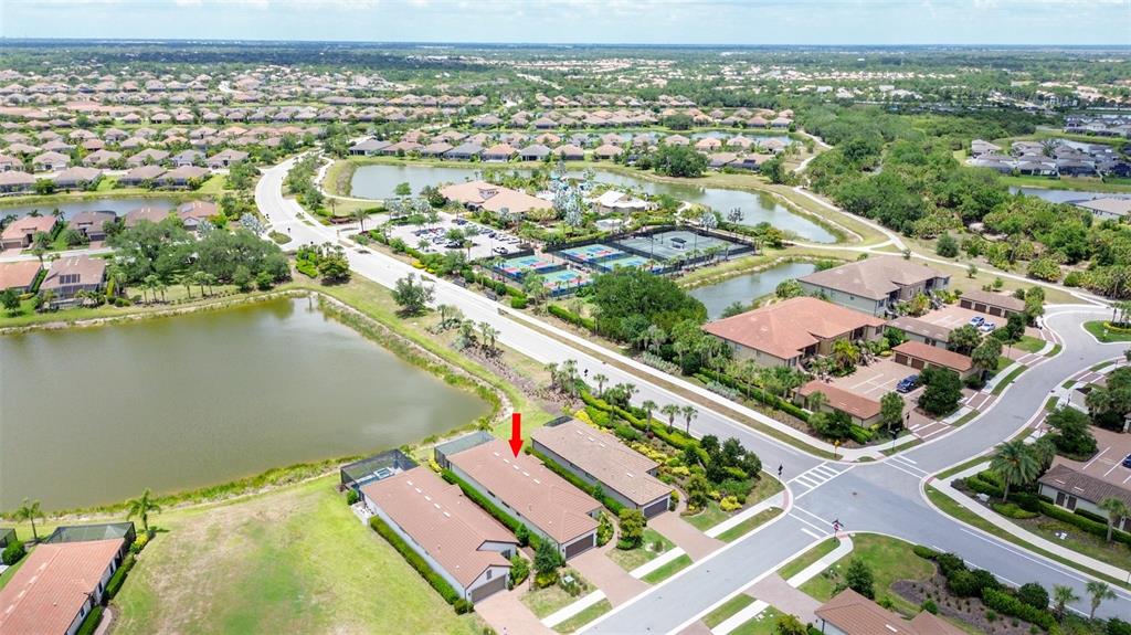 An aerial view shows a residential neighborhood with a lake, tennis courts, and houses — 5362 CICERONE STREET, SARASOTA, FL