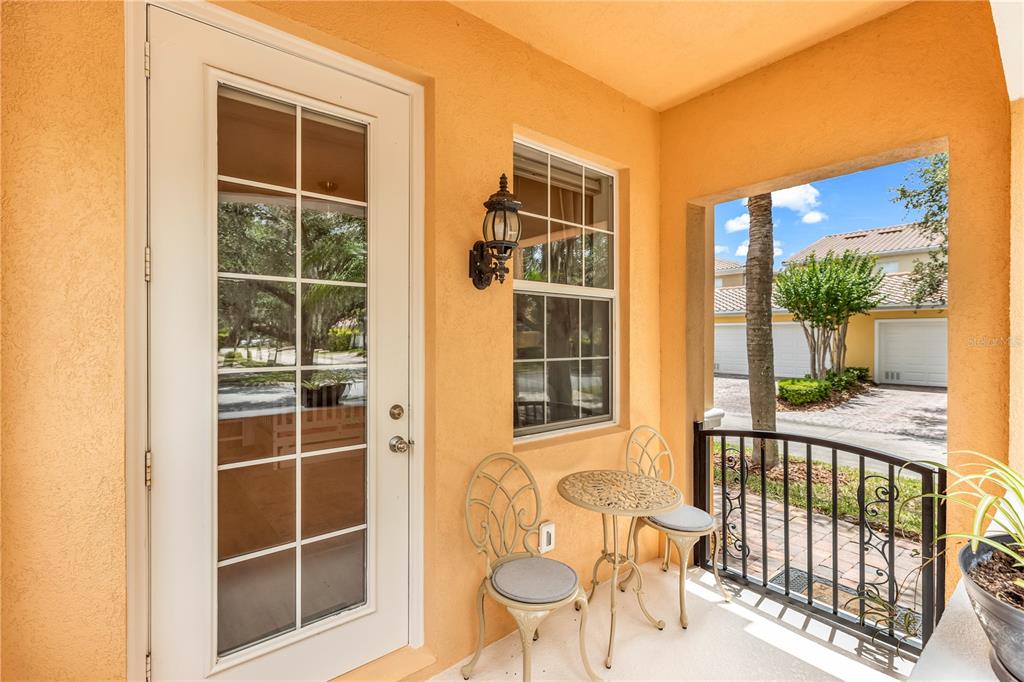 A small covered patio features a glass-paneled door, a window, and a bistro table set — 8418 LEATHERLEAF LANE, ORLANDO, FL