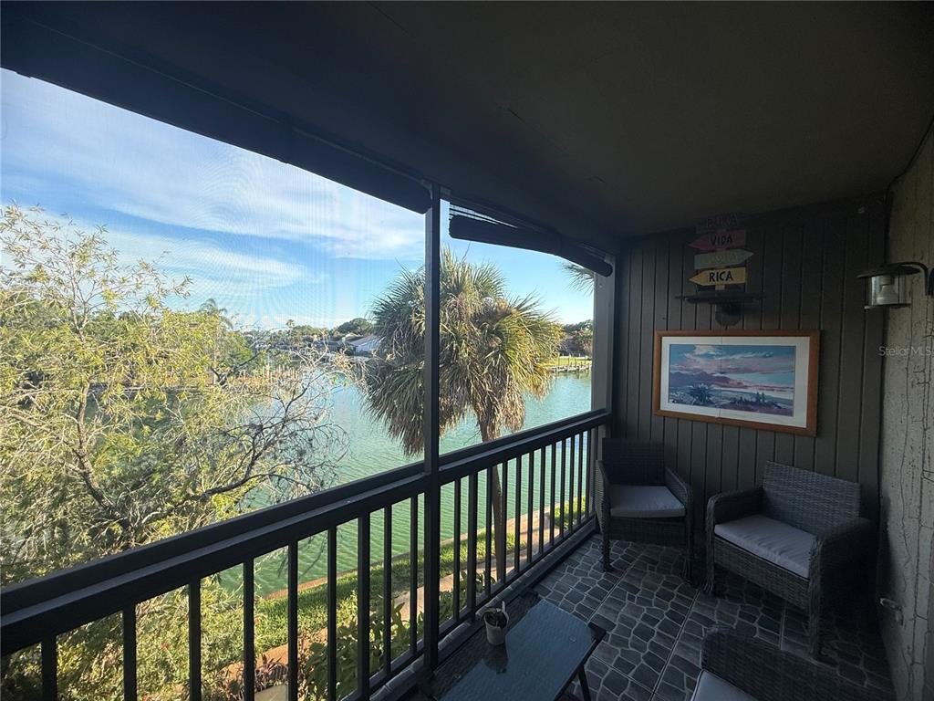 A screened-in balcony overlooks a canal with palm trees and a view of neighboring homes — 6319 NEWTOWN CIRCLE UNIT 19B6, TAMPA, FL
