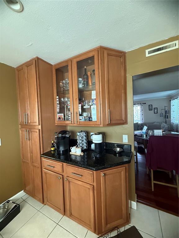 A kitchen coffee station features wood cabinetry, black granite countertops, and a glass-front display cabinet — 6319 NEWTOWN CIRCLE UNIT 19B6, TAMPA, FL