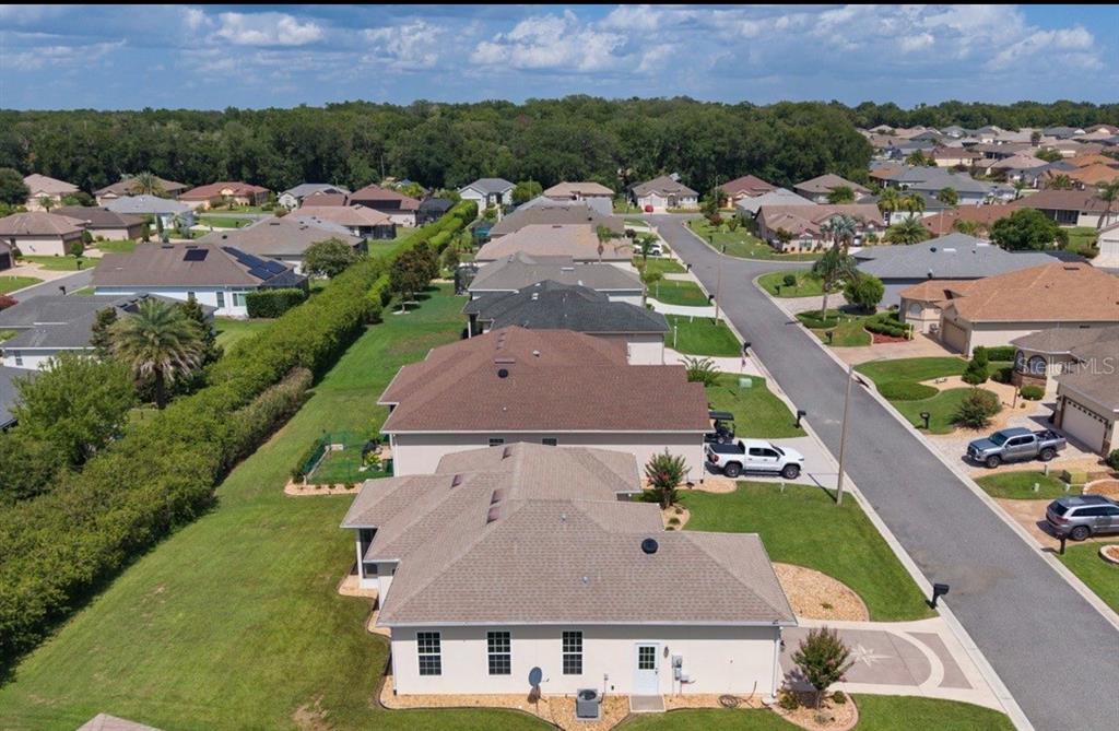 An aerial view of a suburban neighborhood featuring several single-family homes with brown shingled roofs — 10949 SE 169TH LANE, SUMMERFIELD, FL