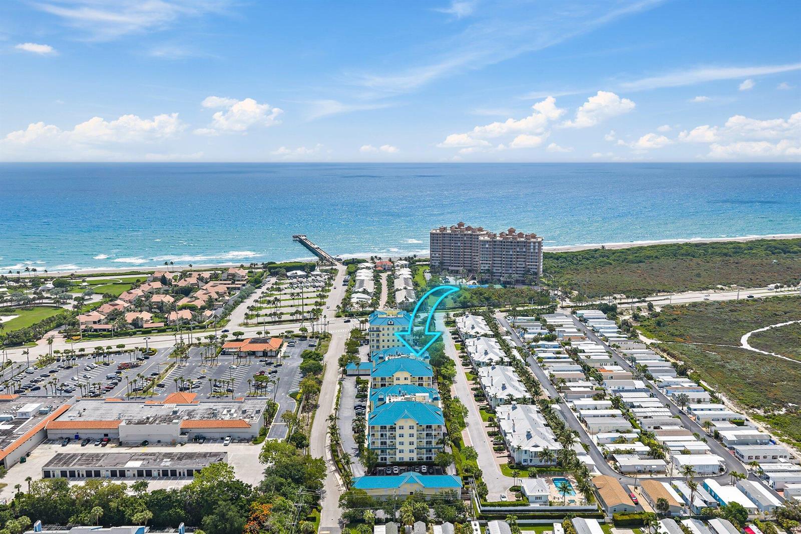 An aerial view shows a multi-story residential building complex near a beach and pier — 800 Juno Ocean Walk # 303, Juno Beach FL 33408, JUNO BEACH, FL