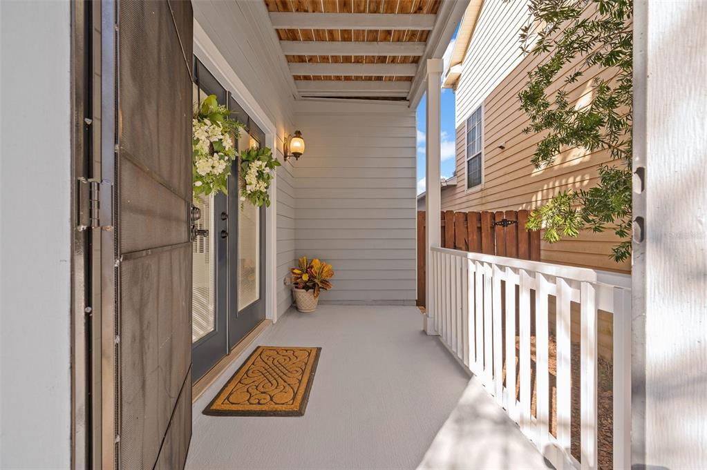 A covered porch features a gray floor, white railing, and double doors with wreaths — 11550 NW 17TH PLACE, GAINESVILLE, FL