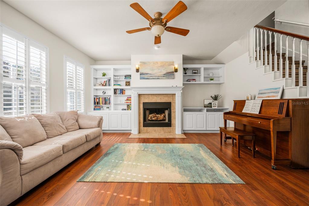 A living room features a fireplace, built-in shelving, a piano, and hardwood floors — 11550 NW 17TH PLACE, GAINESVILLE, FL