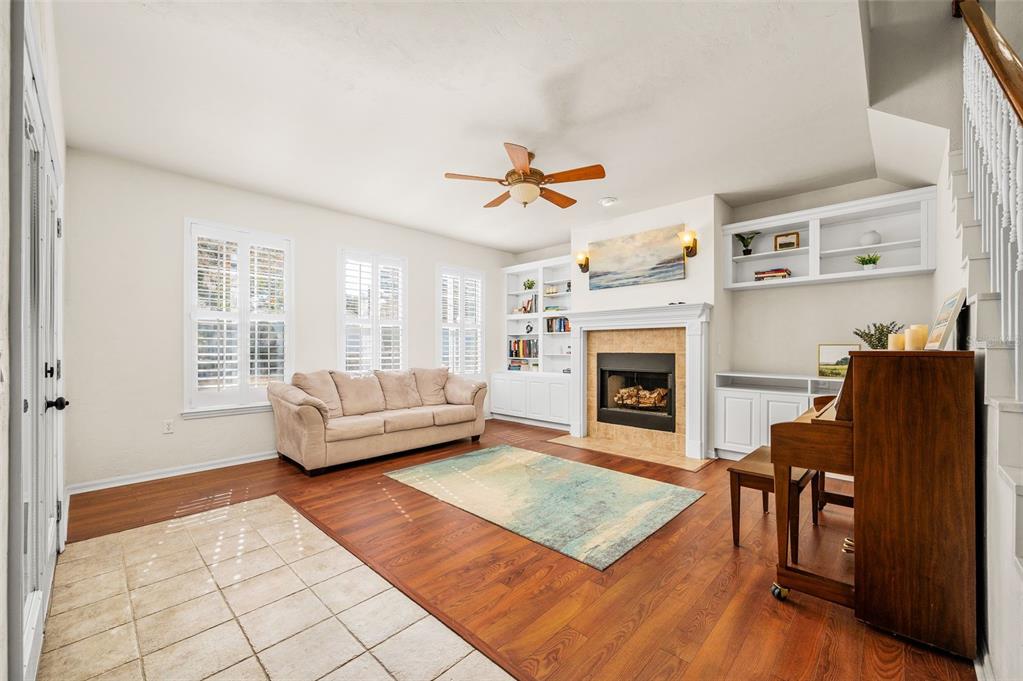 A living room features a fireplace, built-in shelving, a piano, and wood-look flooring — 11550 NW 17TH PLACE, GAINESVILLE, FL