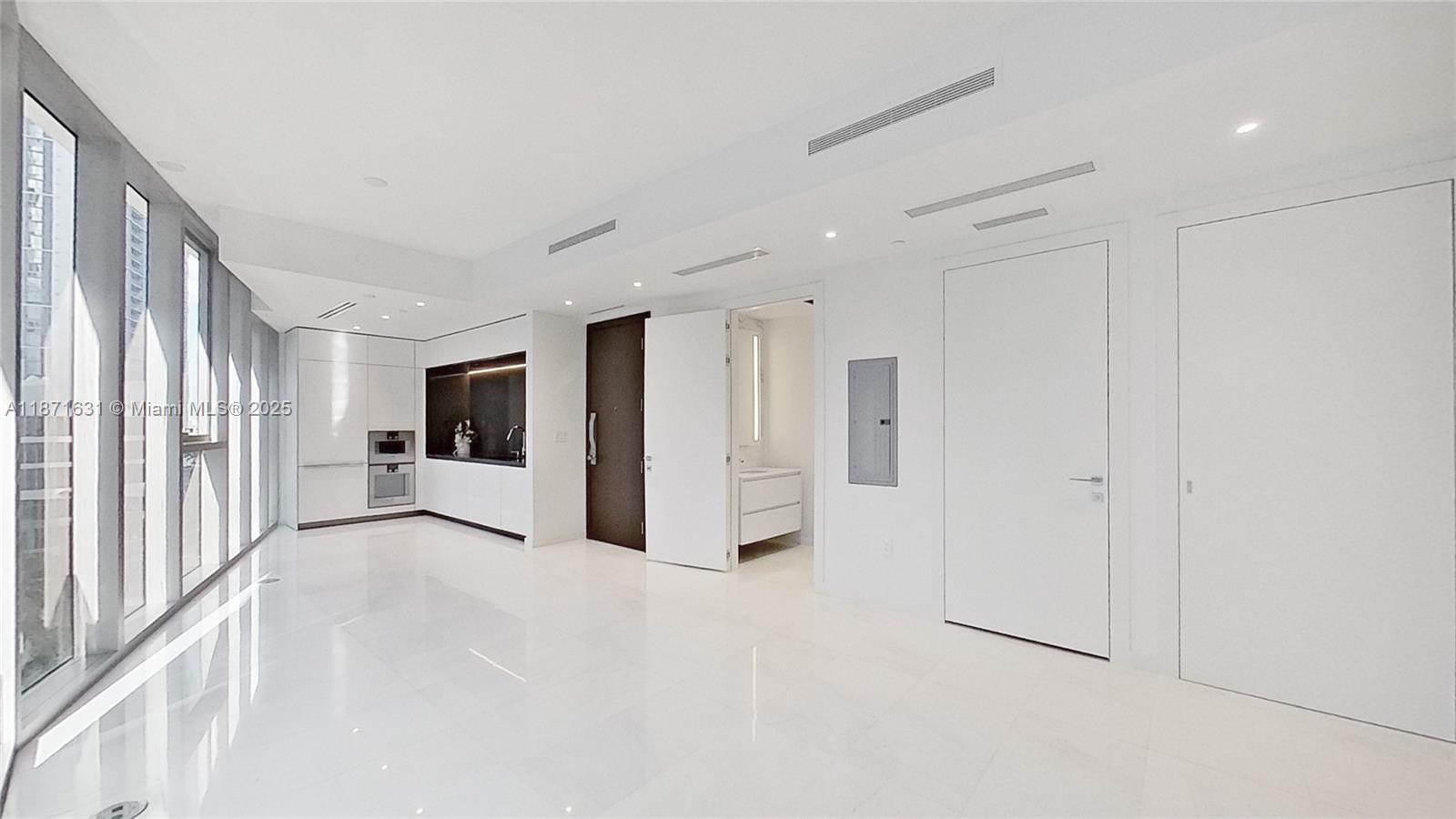 A modern, minimalist room features white tile floors, white cabinetry, and floor-to-ceiling windows — 300 Biscayne Blvd Way # 506E, Miami FL 33131, MIAMI, FL