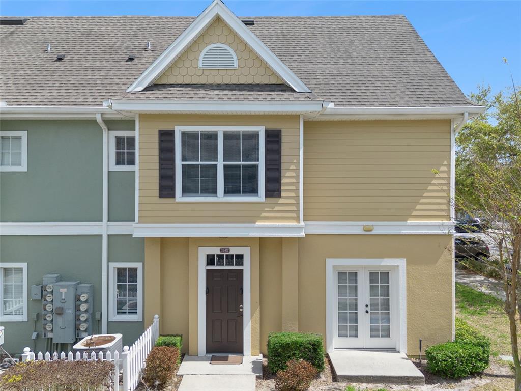 The exterior of a two-story tan townhouse features a brown front door and French doors — 2215 SAN VITTORINO CIRCLE UNIT 102, KISSIMMEE, FL