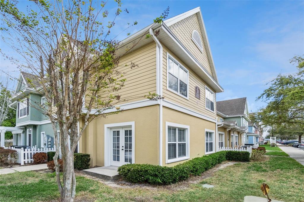 A two-story yellow building with white trim, a small patio, and a manicured hedge — 2215 SAN VITTORINO CIRCLE UNIT 102, KISSIMMEE, FL