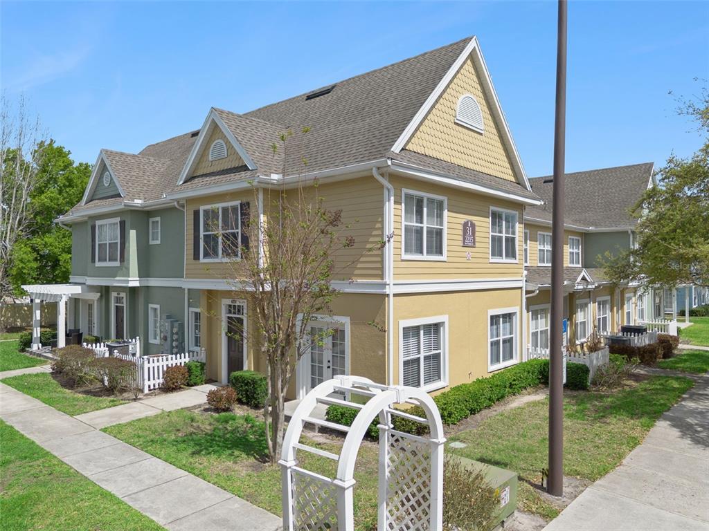 An exterior view of a two-story multi-family building with yellow and green siding — 2215 SAN VITTORINO CIRCLE UNIT 102, KISSIMMEE, FL