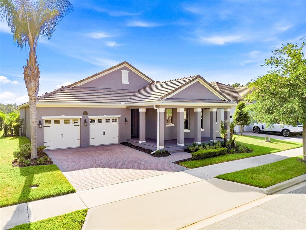 A single-story house with a two-car garage, a covered front porch, and a brick driveway — 10174 MERRYMEETING BAY DRIVE, WINTER GARDEN, FL