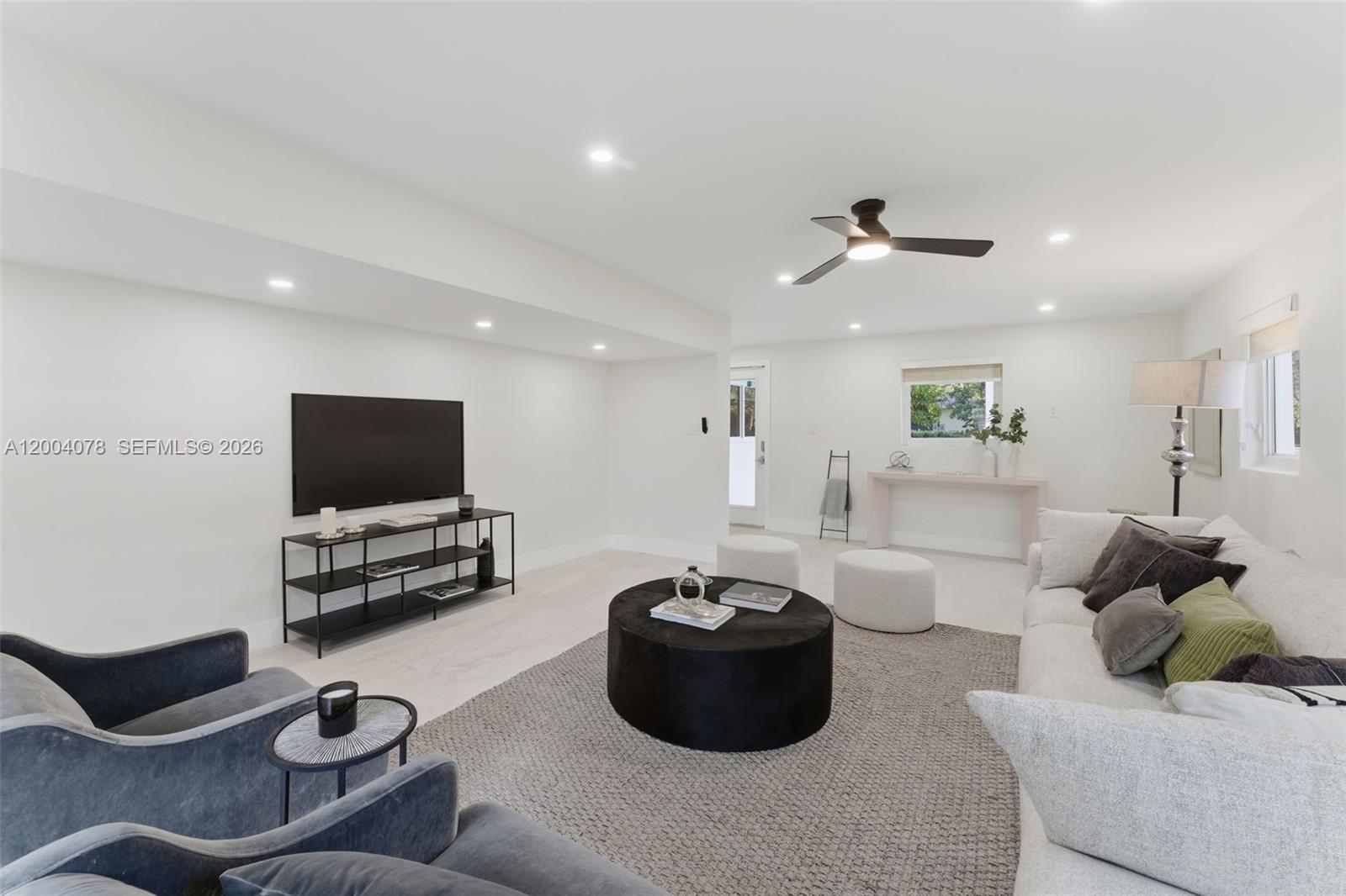 A modern living room features white walls, a gray area rug, and dark furniture — 13225 SW 83rd Ct, Pinecrest FL 33156, PINECREST, FL