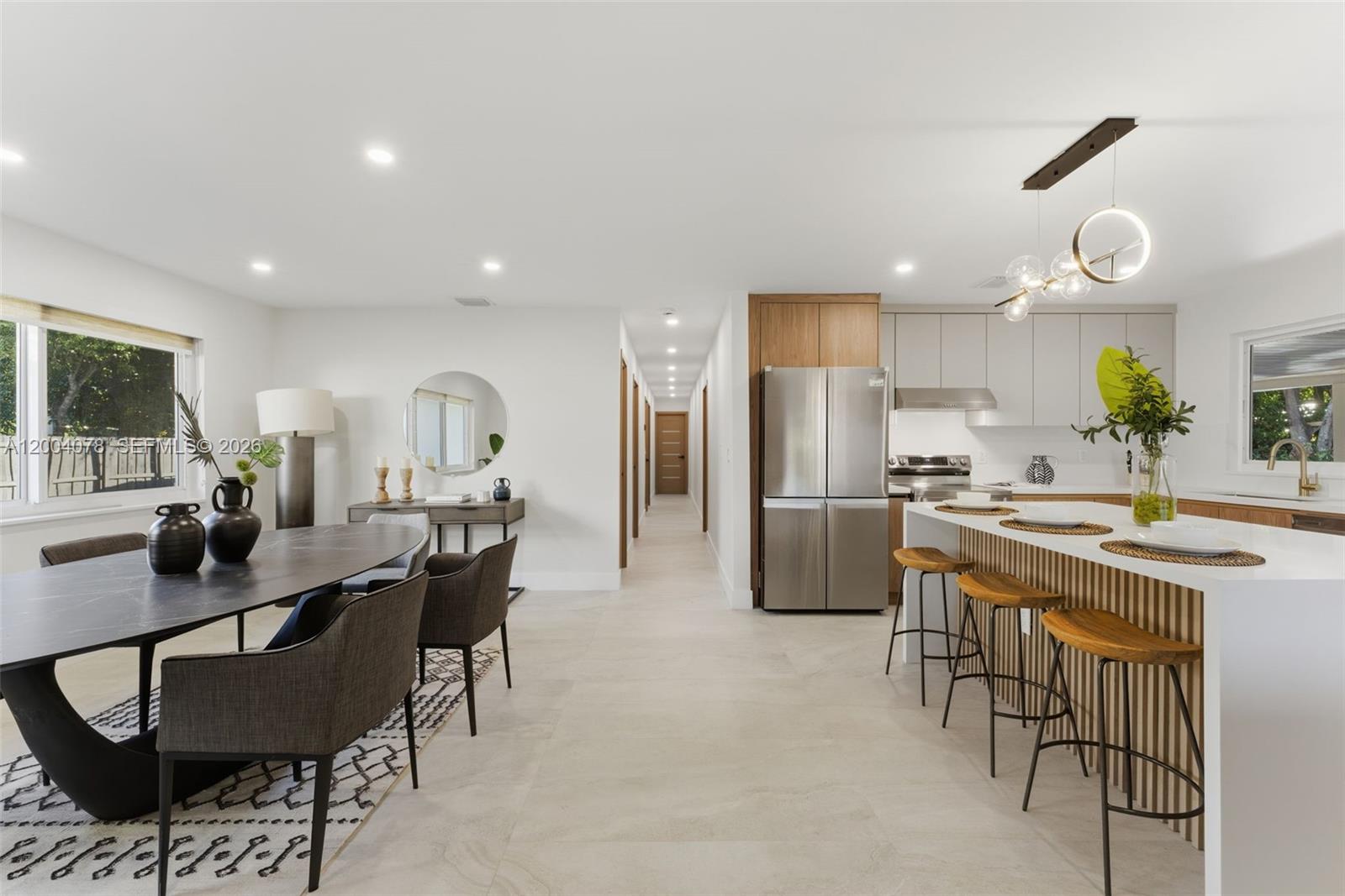 A modern open-concept kitchen and dining area features a large island and marble-topped table — 13225 SW 83rd Ct, Pinecrest FL 33156, PINECREST, FL