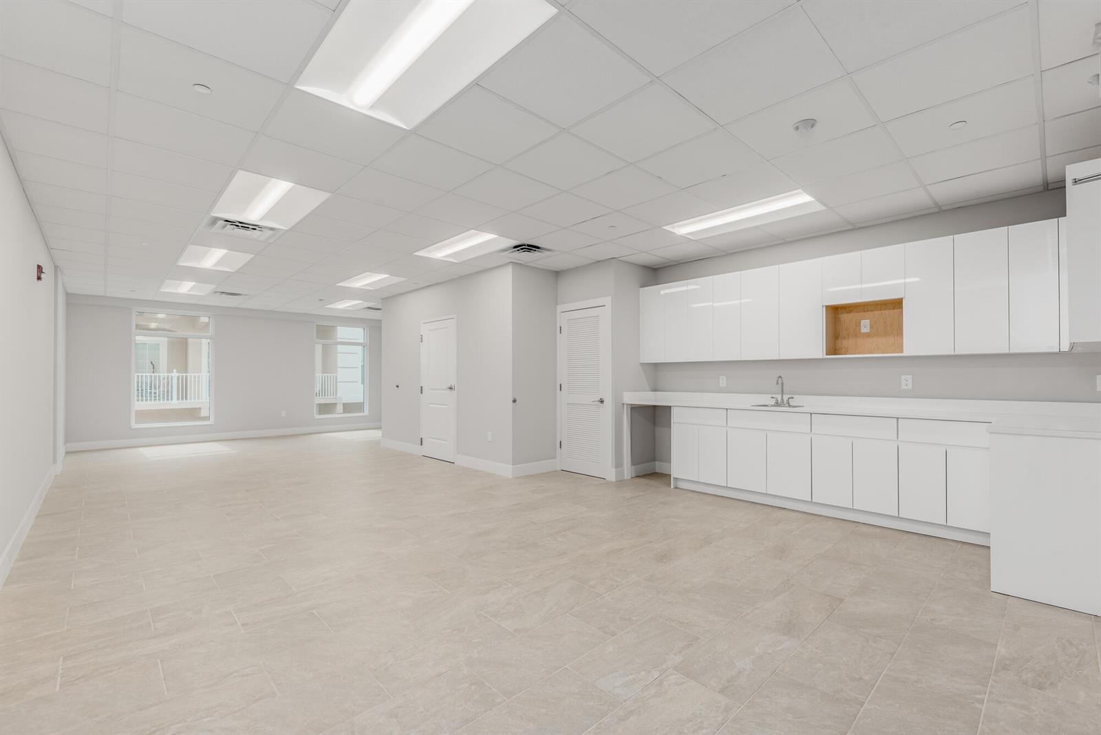 An empty office space features white cabinetry, a sink, tile flooring, and recessed ceiling lights — 41 SW Seminole Street # 210, Stuart FL 34994, STUART, FL