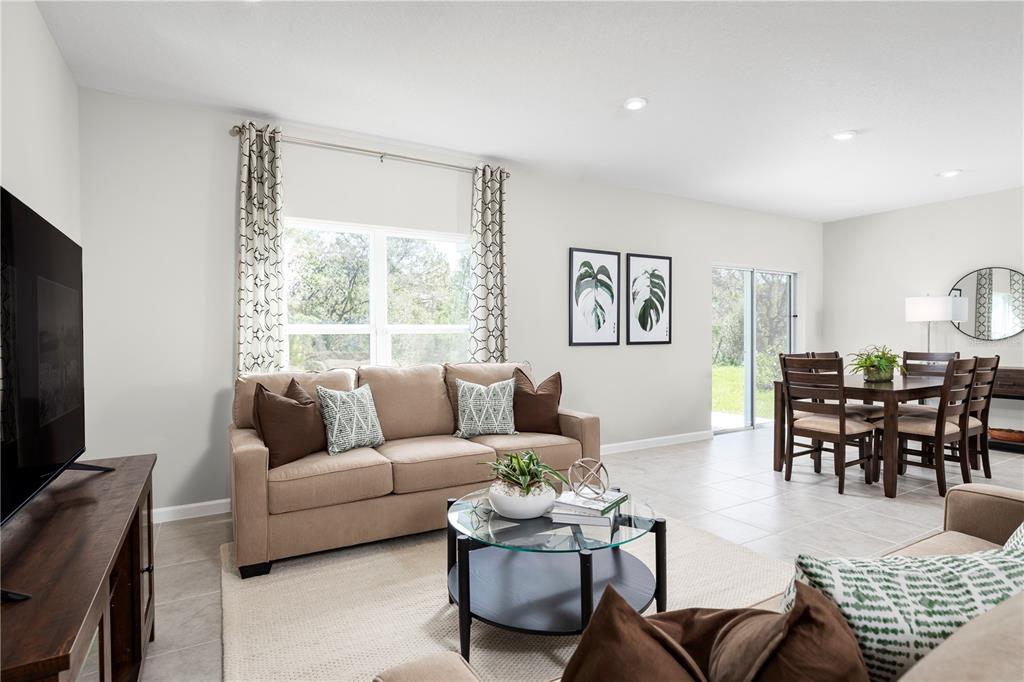 A living room with a beige sofa, glass coffee table, and adjacent dining area — 1111 HICKORY BRANCH DRIVE, LAKELAND, FL