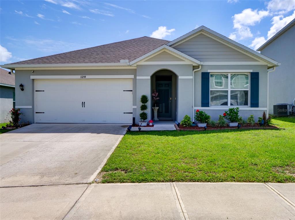 A single-story suburban house with a gray stucco exterior, a two-car garage, and a lawn — 11244 AMBER RIDGE DRIVE, ZELLWOOD, FL