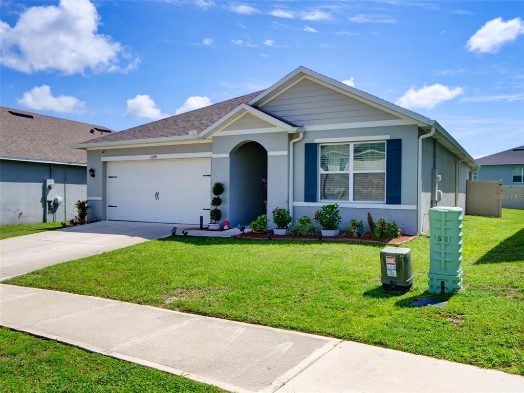 A single-story house with a white garage door, gray siding, and a green utility box — 11244 AMBER RIDGE DRIVE, ZELLWOOD, FL