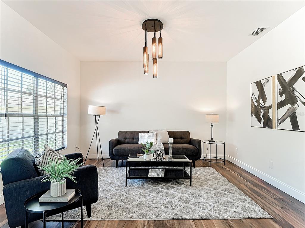 A living room features a dark sofa, a patterned rug, and a modern pendant light — 130 16TH AVENUE NE, NAPLES, FL