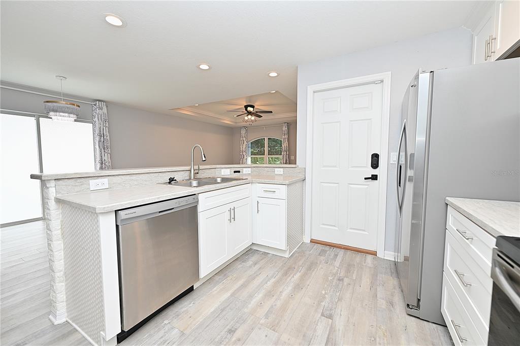 A kitchen with white cabinets, stainless steel appliances, and light wood-look flooring — 5662 TOWER PALMS LANE, LAKELAND, FL
