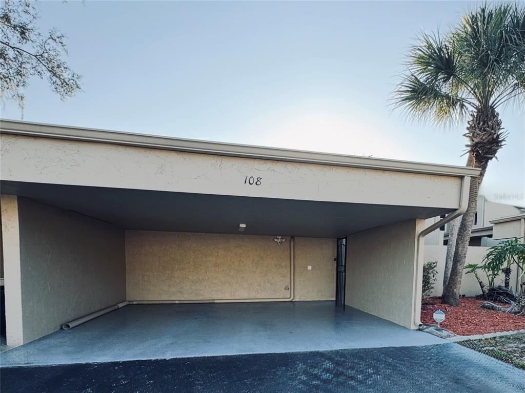 A covered carport with a concrete floor and the number 108 displayed above the opening — 108 MADRID DRIVE UNIT D, CASSELBERRY, FL