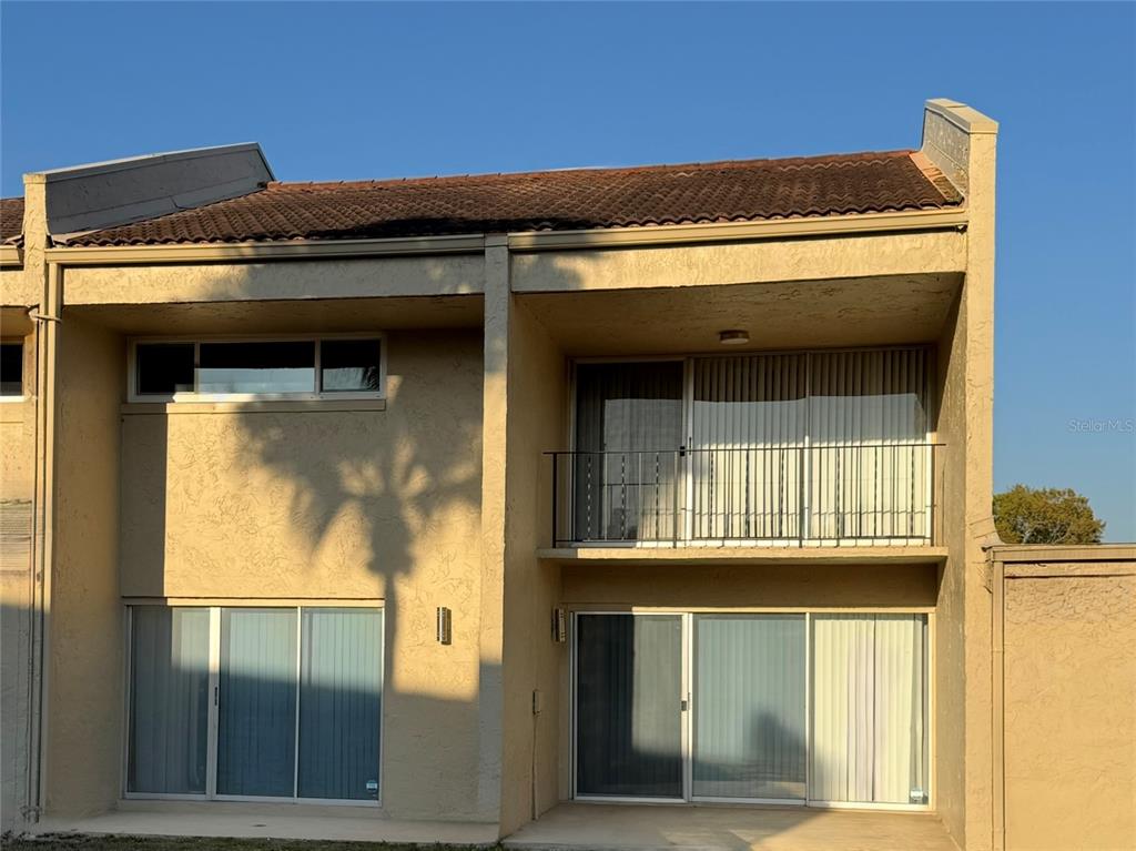 A two-story tan stucco townhouse exterior features a second-floor balcony and sliding glass doors — 108 MADRID DRIVE UNIT D, CASSELBERRY, FL