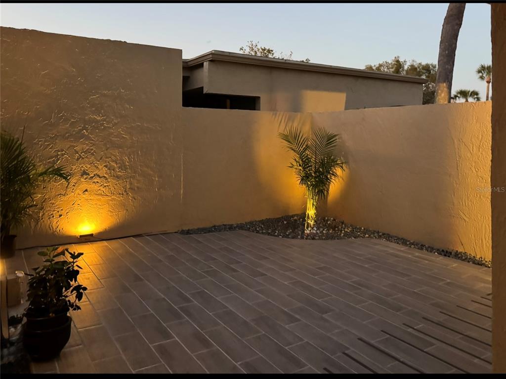A paved patio features two small palm trees illuminated by ground-level accent lighting against walls — 108 MADRID DRIVE UNIT D, CASSELBERRY, FL