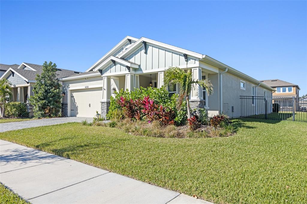 A single-story house with a light-colored facade, a garage, and a landscaped front yard — 6232 SEA AIR DRIVE, APOLLO BEACH, FL