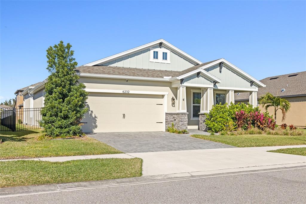 A single-story house with a beige garage, stone accents, and a light green gable roof — 6232 SEA AIR DRIVE, APOLLO BEACH, FL