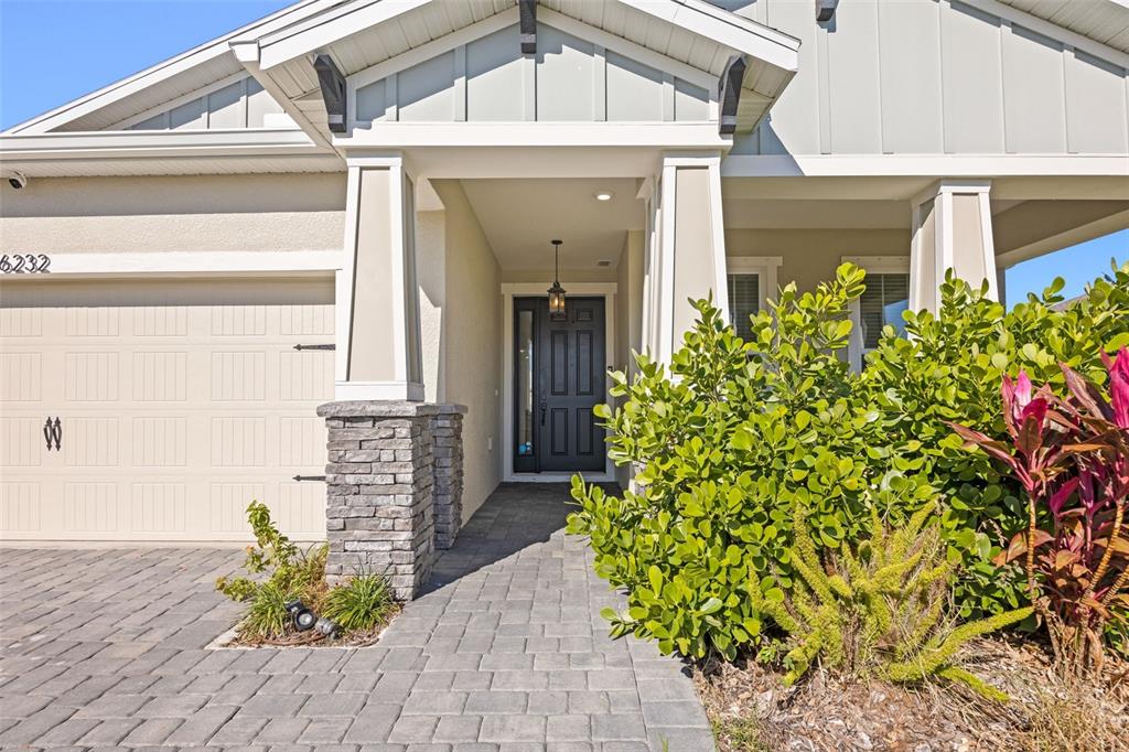 The exterior of a house features a paved walkway, a stone-based pillar, and landscaping — 6232 SEA AIR DRIVE, APOLLO BEACH, FL