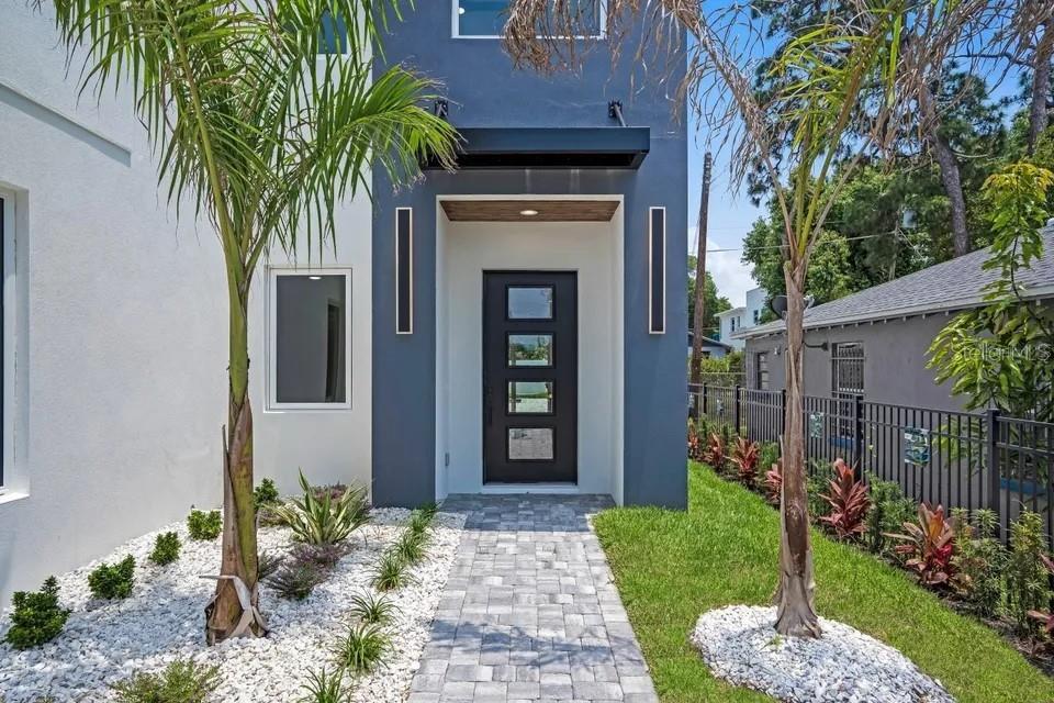 A modern house exterior features a dark gray entrance, a paved walkway, and palm trees — 1156 COCOANUT AVENUE, SARASOTA, FL