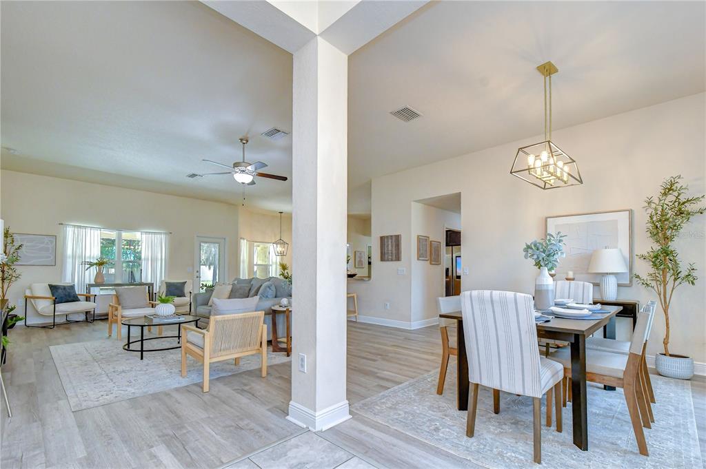 An open-concept living and dining area features light wood-look flooring and neutral wall colors — 3358 PONYTAIL COURT, SPRING HILL, FL