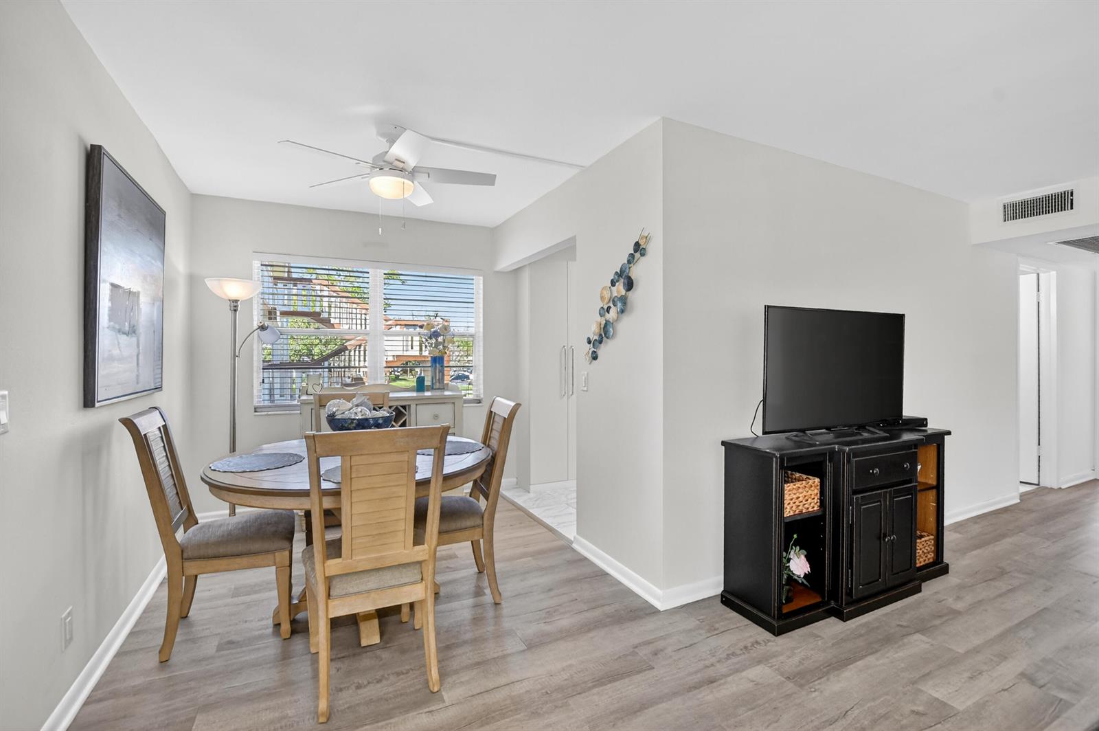 A dining area with a round wooden table sits next to a living room space — 150 Mansfield D # 150, Boca Raton FL 33434, BOCA RATON, FL