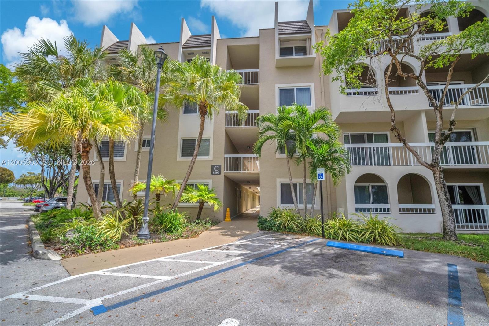 A multi-story apartment building with a central walkway, palm trees, and a handicap parking space — 8103 Camino Real # 314, Miami FL 33143, MIAMI, FL