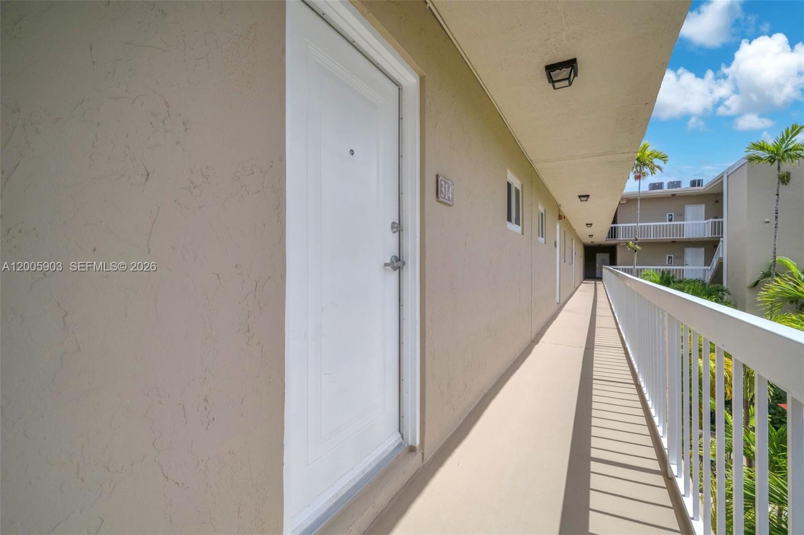 An exterior walkway leads past a white door labeled 314 in a multi-story apartment complex — 8103 Camino Real # 314, Miami FL 33143, MIAMI, FL