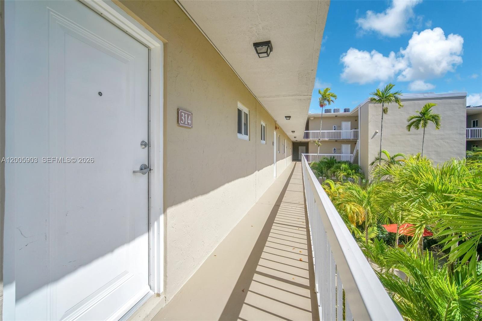 An outdoor apartment building walkway features a white door labeled 314 and a metal railing — 8103 Camino Real # 314, Miami FL 33143, MIAMI, FL