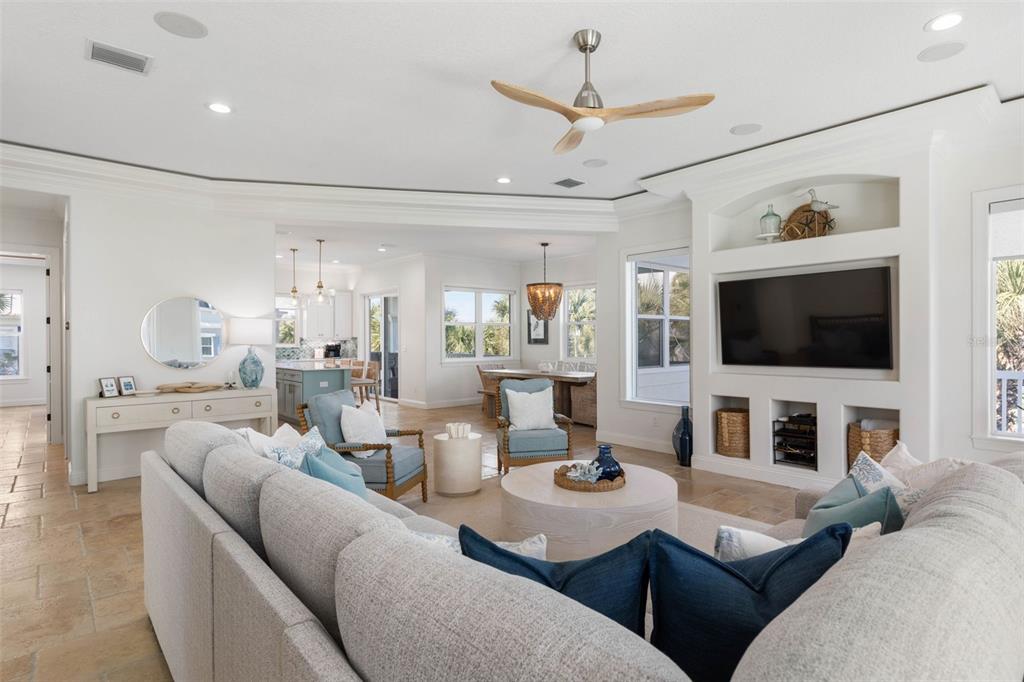 A bright, open-concept living room features a large sectional, built-in media center, and tile flooring — 501 CINNAMON BEACH LANE, PALM COAST, FL