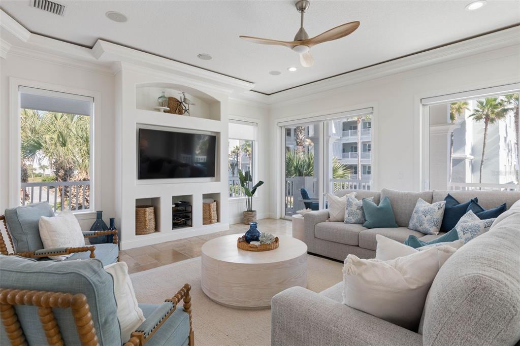 A bright living room features a built-in media center, light-colored furniture, and a ceiling fan — 501 CINNAMON BEACH LANE, PALM COAST, FL