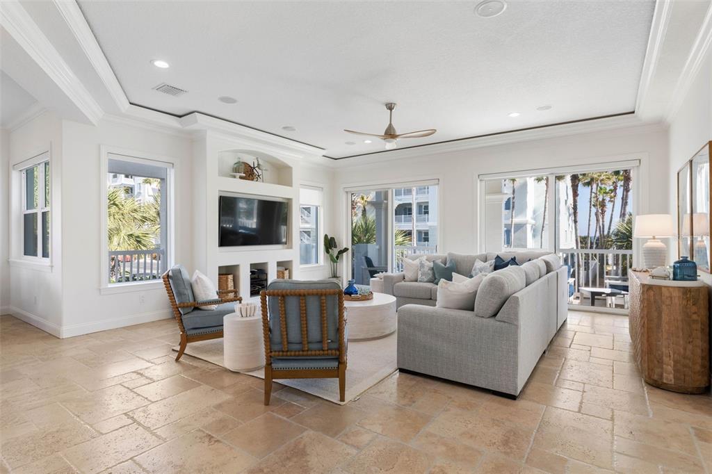 A bright living room features light tile floors, a sectional sofa, and a built-in media unit — 501 CINNAMON BEACH LANE, PALM COAST, FL