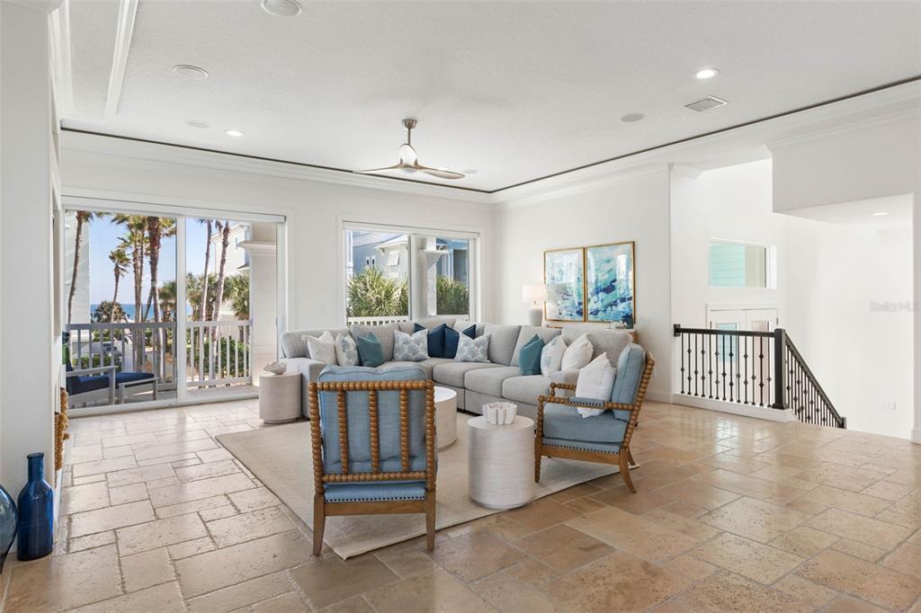 A bright living room features a large sectional sofa, tiled floors, and a balcony view — 501 CINNAMON BEACH LANE, PALM COAST, FL