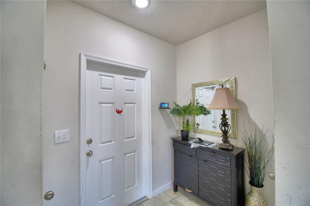 An entryway features a white door, a dark console table, a mirror, and a lamp — 1533 MAJESTIC LANE, WINTER HAVEN, FL