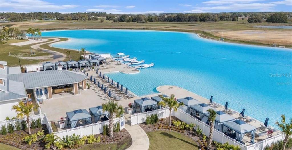 An aerial view shows a large turquoise lagoon with cabanas and a poolside bar area — 31406 MANGO FADE WAY, SAN ANTONIO, FL