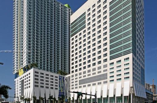 A low-angle exterior view of two modern high-rise buildings against a clear blue sky — 175 SW 7th St # 2102, Miami FL 33130, MIAMI, FL
