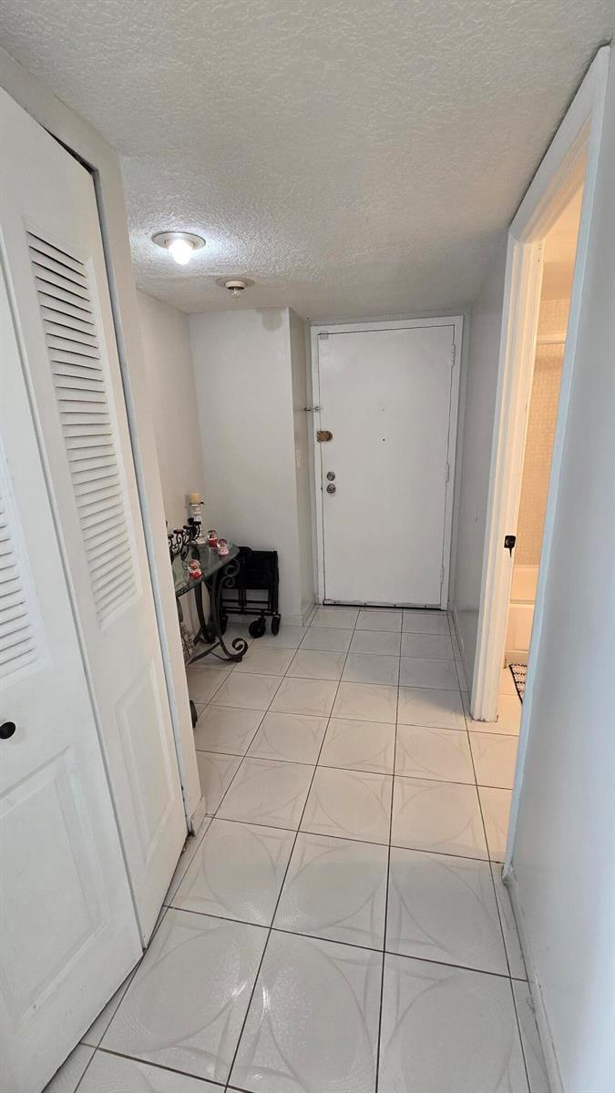 A tiled entryway features a white door, a louvered closet door, and a small console table — 4164 Inverrary Drive # 601, Lauderhill FL 33319, LAUDERHILL, FL