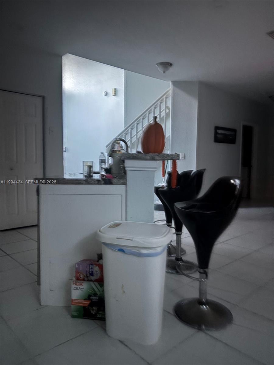 A kitchen island with bar stools sits in front of a staircase in this room — 3544 Dunes Vista Dr, Pompano Beach FL 33069, POMPANO BEACH, FL