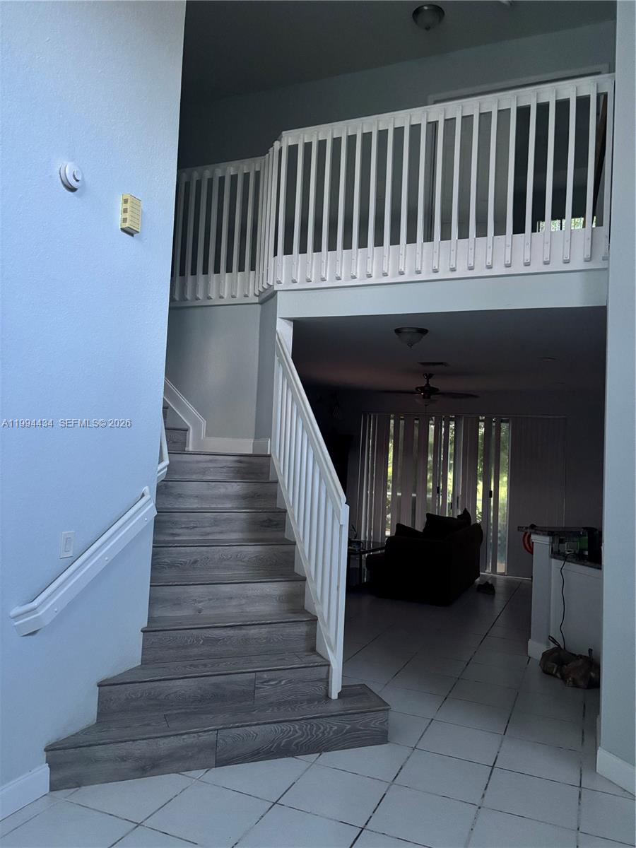 A staircase with wood-look steps leads to an upper landing with white railings — 3544 Dunes Vista Dr, Pompano Beach FL 33069, POMPANO BEACH, FL