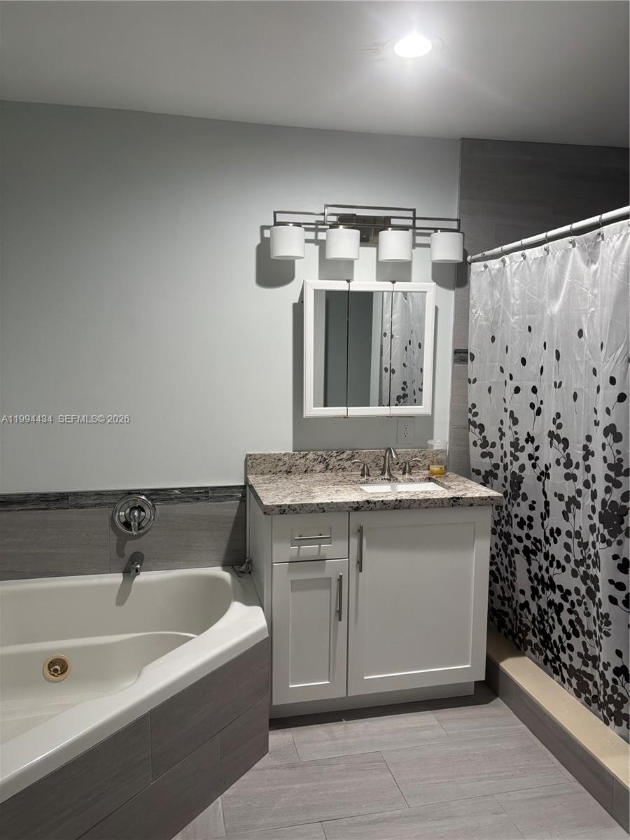 A bathroom features a white vanity with a granite countertop, a tub, and a shower — 3544 Dunes Vista Dr, Pompano Beach FL 33069, POMPANO BEACH, FL