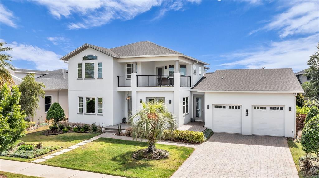 A two-story white house with a balcony, a two-car garage, and a paved driveway — 12521 FARADAY LANE, ORLANDO, FL