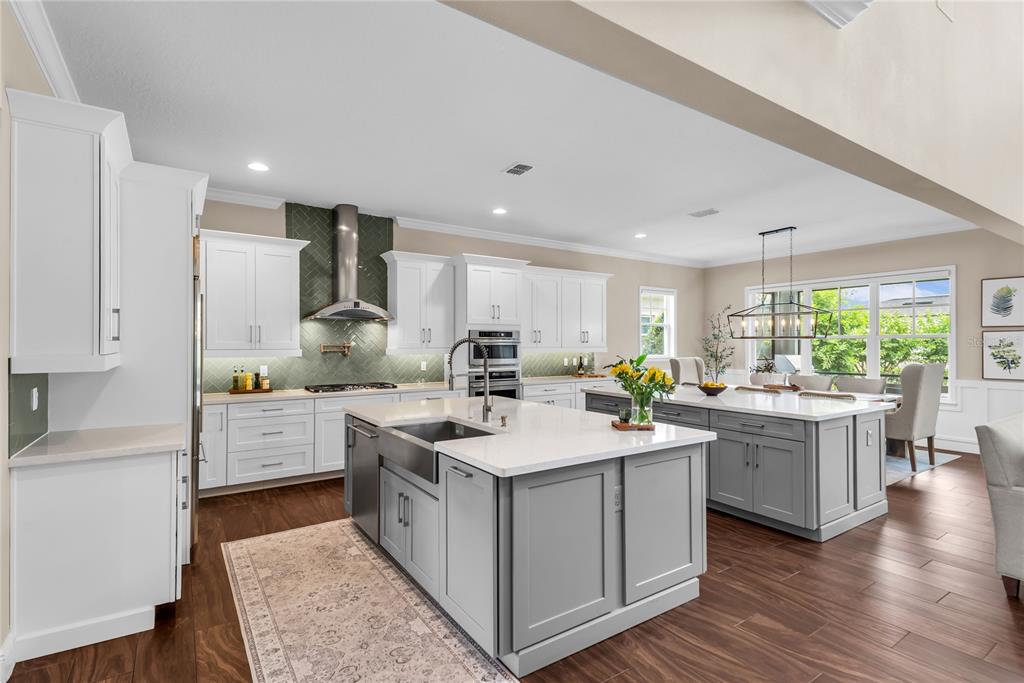 A kitchen features white cabinets, gray islands with quartz countertops, and a green herringbone backsplash — 12521 FARADAY LANE, ORLANDO, FL